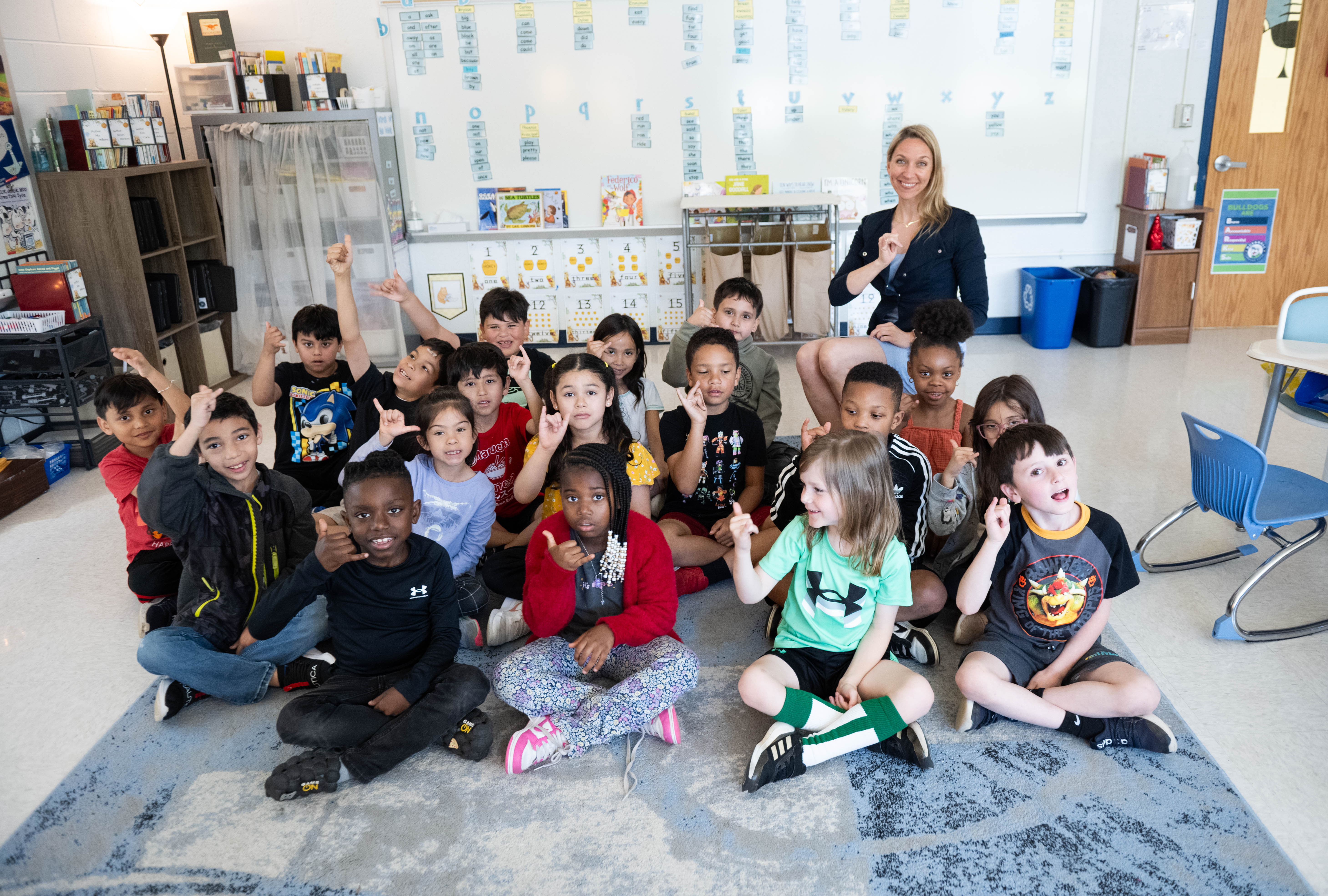 a teacher and her students sit on a rug