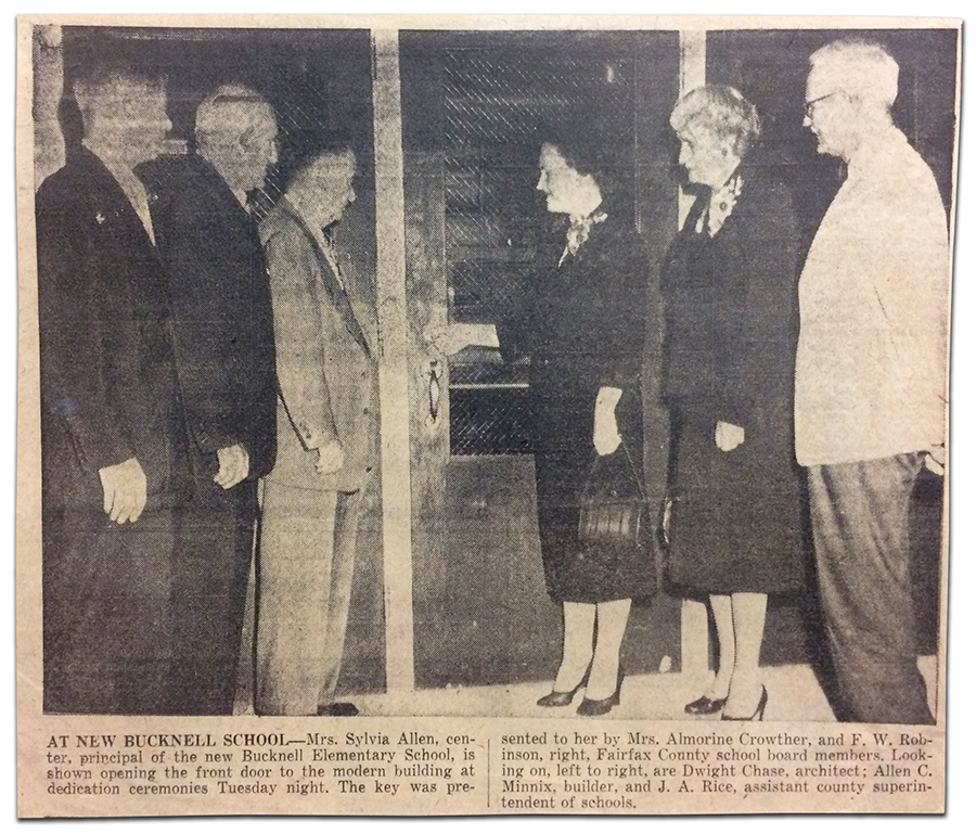 Newspaper clipping from an article about the dedication ceremony for Bucknell Elementary School. A black and white photograph and its caption are shown. In the picture, six adults are standing at the front doors to the school. Principal Sylvia Allen is unlocking the door. The caption reads: At new Bucknell School - Mrs. Sylvia Allen, center, principal of the new Bucknell Elementary School, is shown opening the front door to the modern building at dedication ceremonies Tuesday night. The key was presented to her by Mrs. Almorine Crowther, and F. W. Robinson, right, Fairfax County school board members. Looking on, left to right, are Dwight Chase, architect; Allen C. Minnix, builder, and J. A. Rice, assistant county superintendent of schools. 